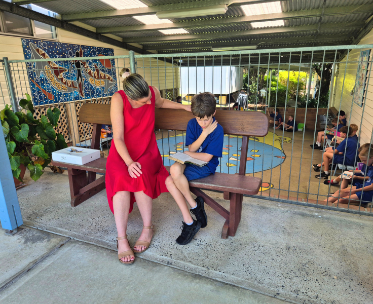 A teacher sitting with a student reading